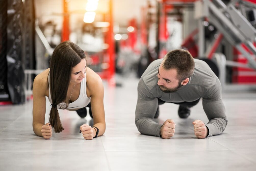Een man en een vrouw voeren de Plank-oefening uit, ontworpen voor alle spiergroepen